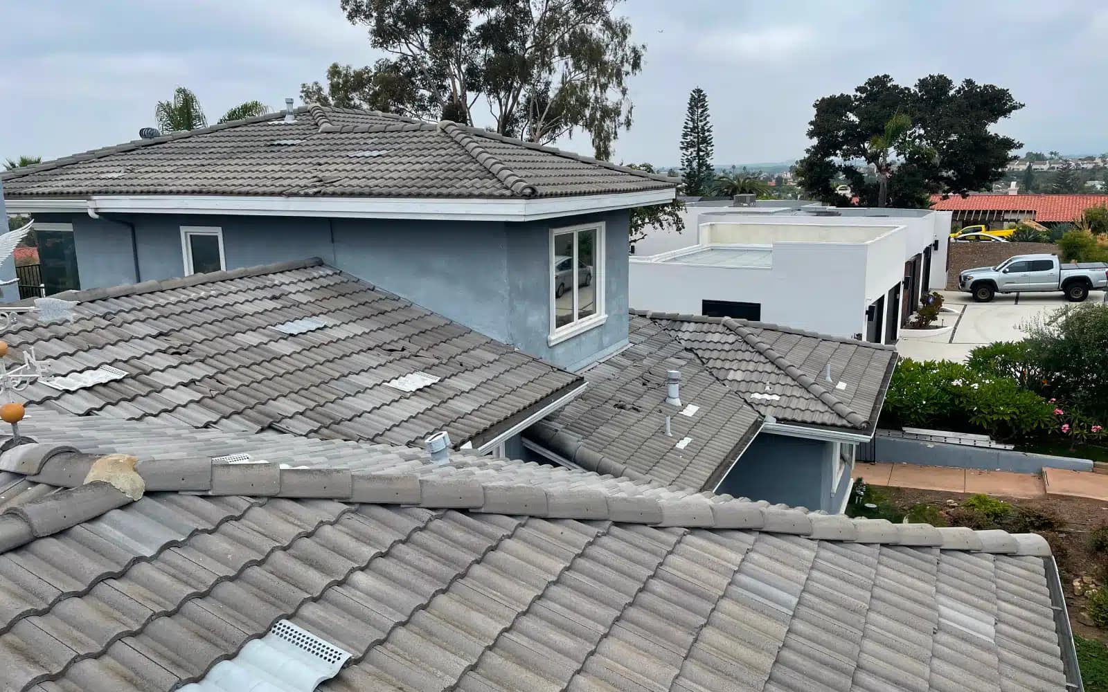 Aging concrete tile roofing across multiple roof sections before a concrete tile roof replacement in Carlsbad, CA.