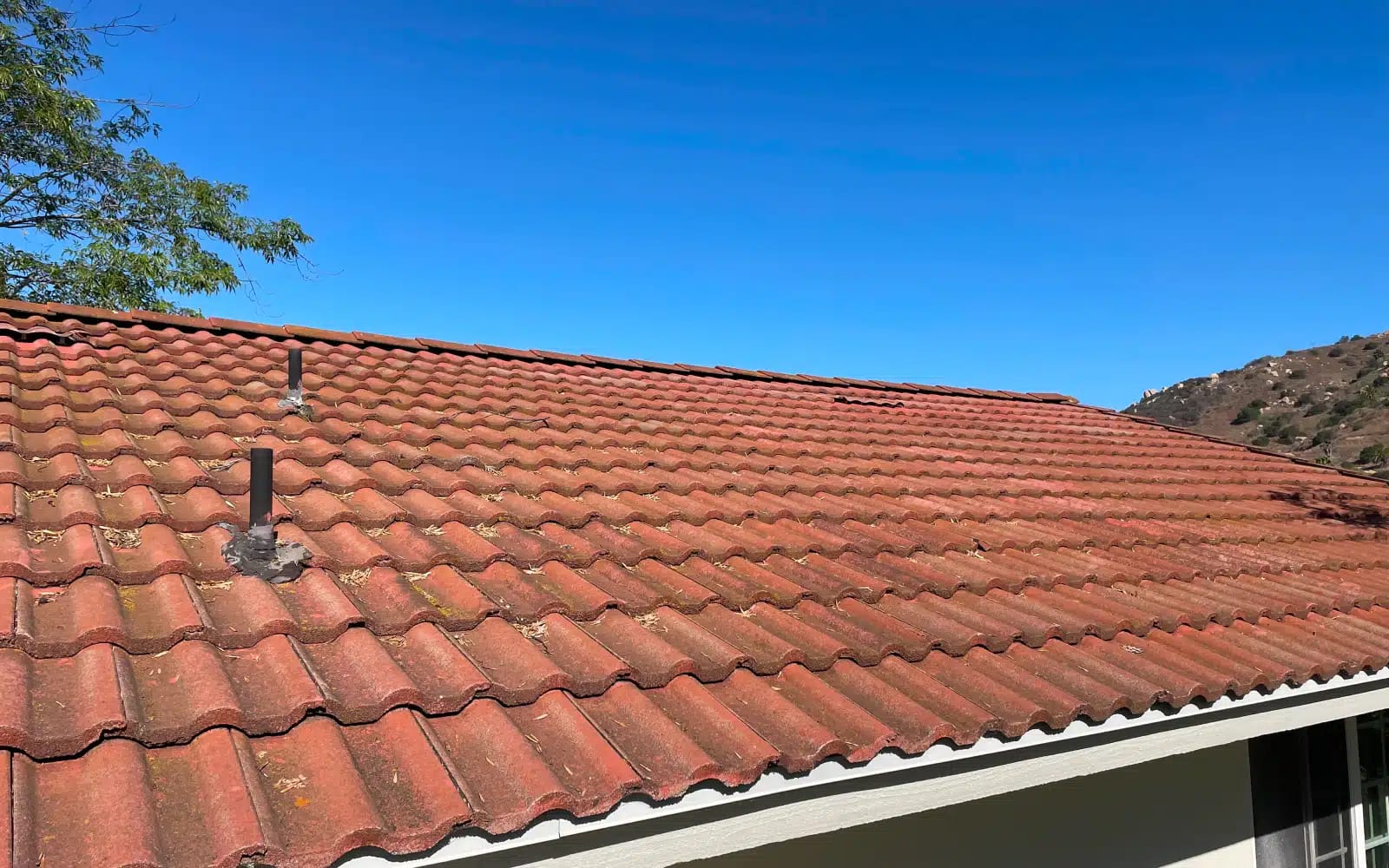 Aging concrete tile roofing system in San Marcos, CA before full roof replacement, showing surface wear and roof penetrations.