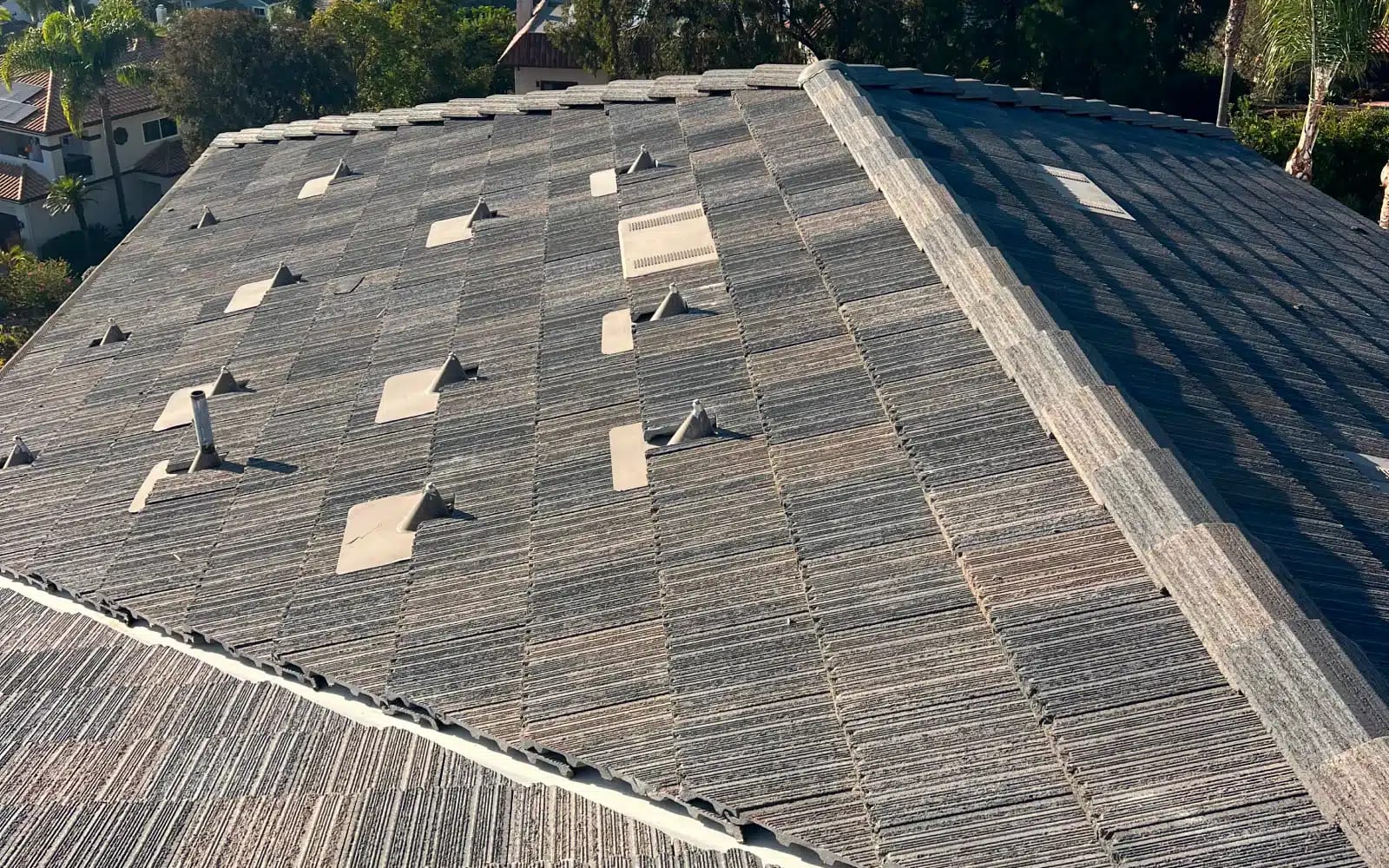Completed concrete tile roof replacement in Carlsbad, California featuring uniform tile alignment and finished ridge detailing.