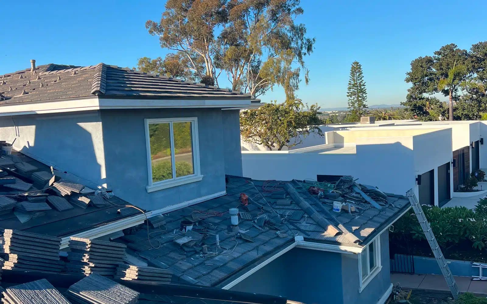 Concrete tile roof tear-off in progress showing exposed roof sections during full roof replacement in Carlsbad, CA.