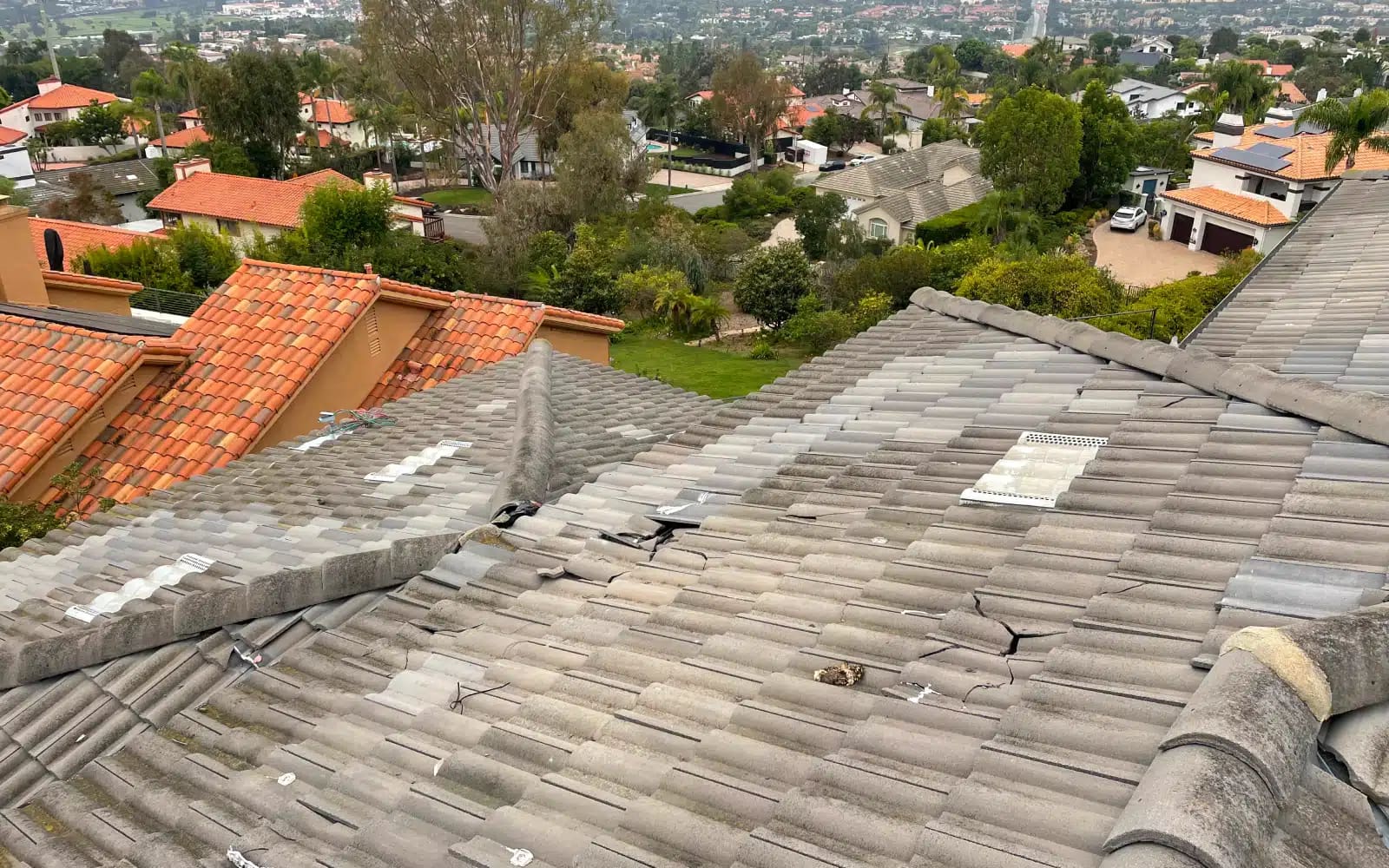 Damaged concrete roof tiles and ridge area showing cracking and weather exposure prior to roof replacement in Carlsbad, California.