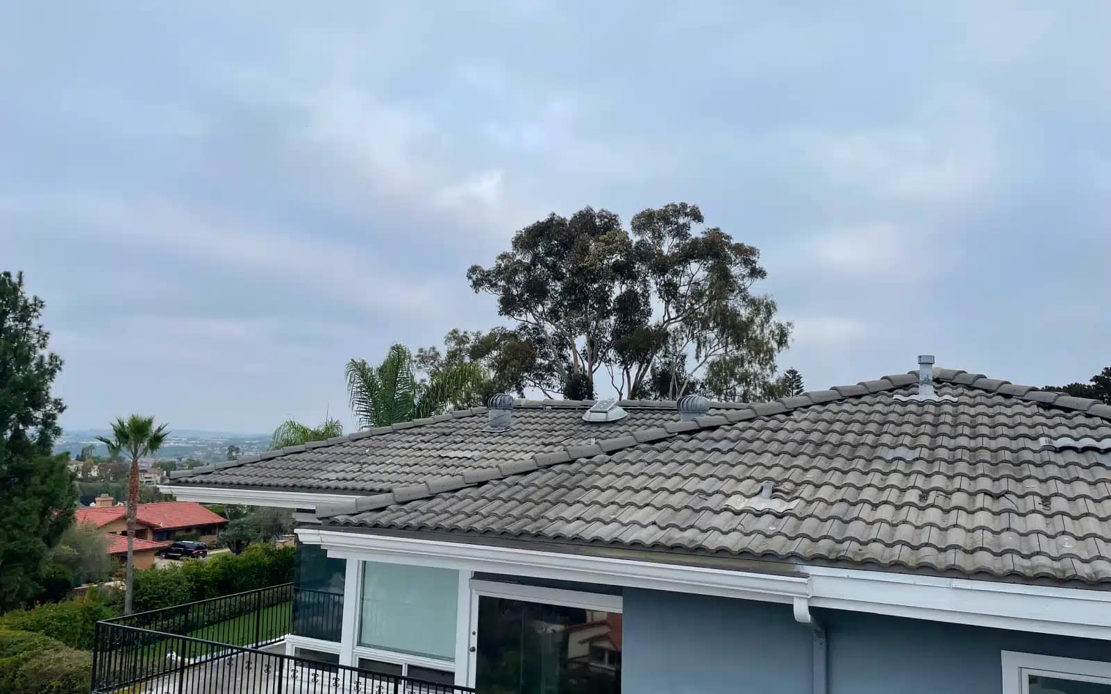 Existing concrete tile roof in Carlsbad, California showing aging tiles and original roof configuration prior to full replacement.
