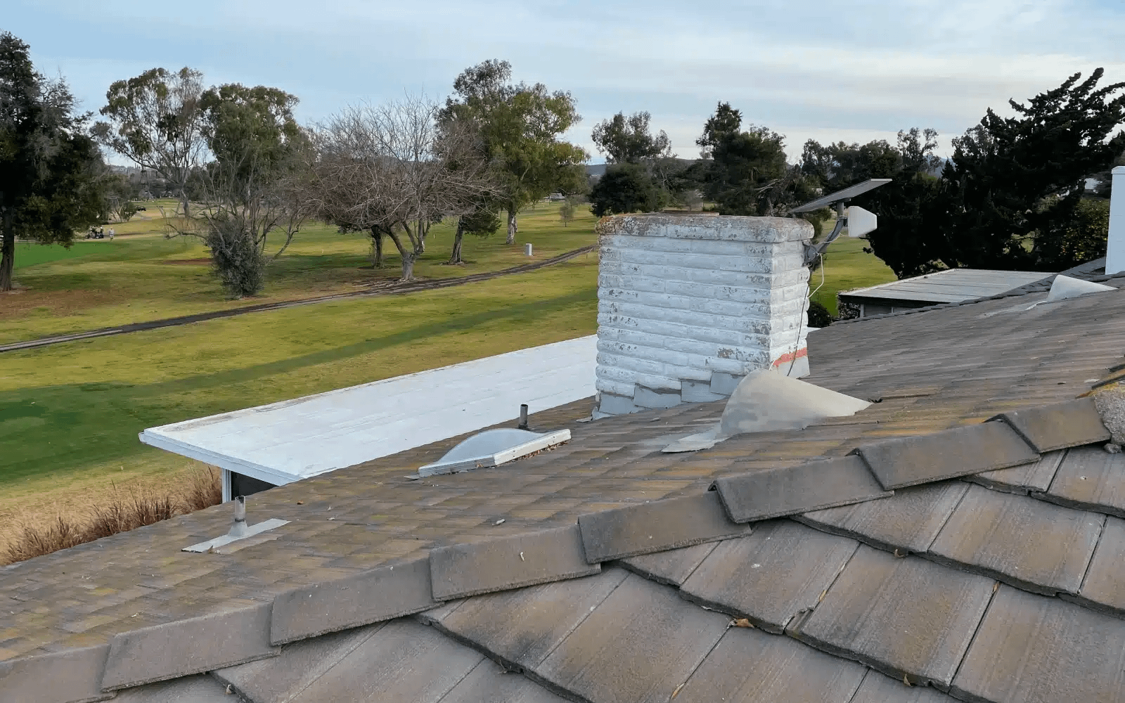 Existing concrete tile roof in Lake San Marcos, CA before GAF solar shingle roof replacement, showing aging tiles and flat roof section prior to system removal.