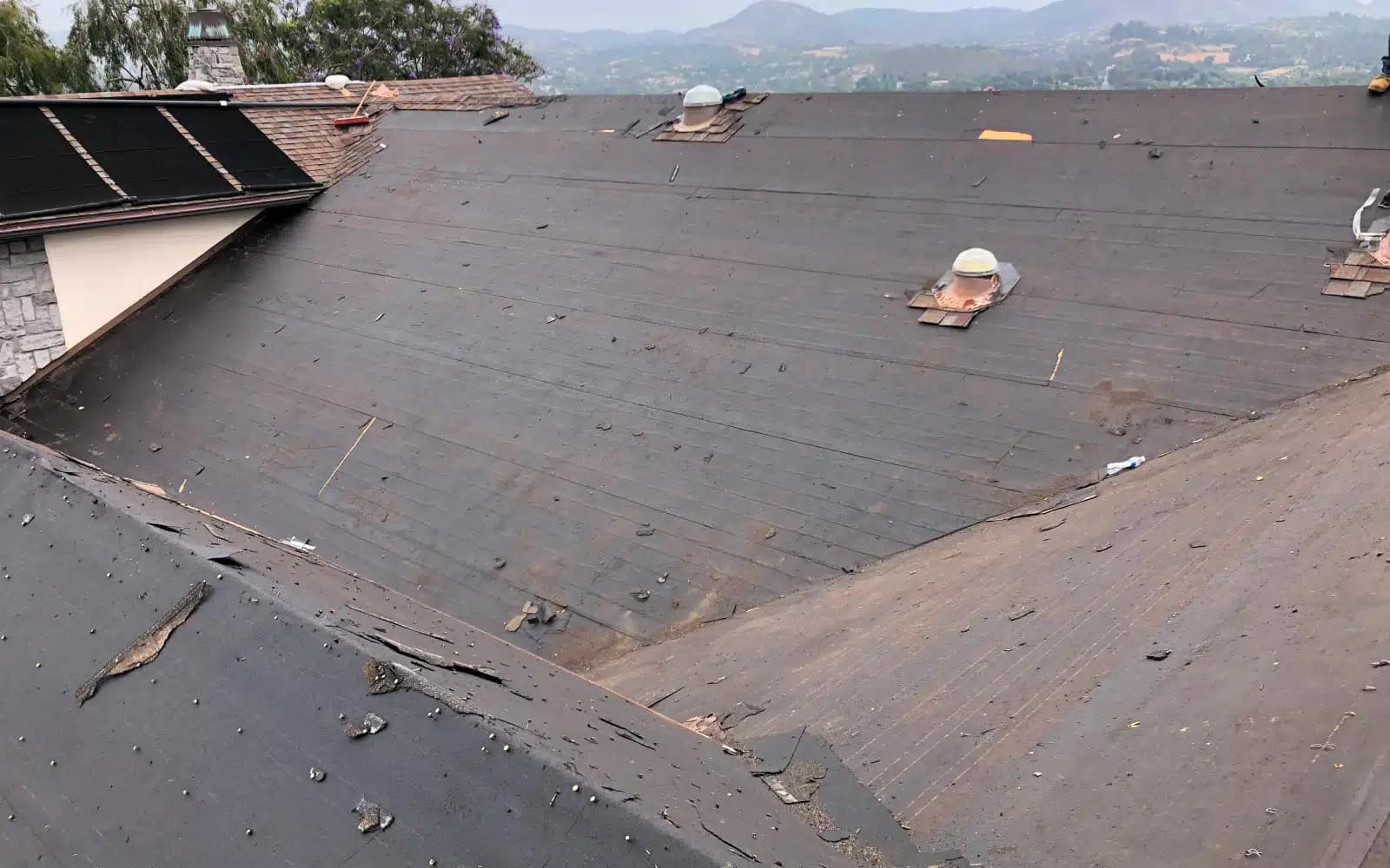 Roof tear-off completed during asphalt shingle roof replacement in Encinitas, CA, exposing existing roof deck and underlayment prior to new system installation.