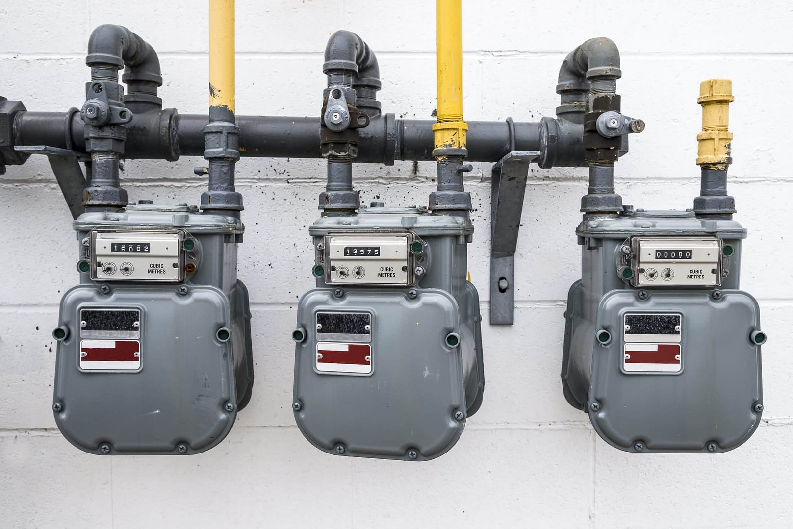 Three gas meters on a wall 3 gas meters and its pipe installed into a wall